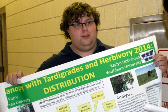 Senior Devin Parry shows his poster to another student at Scholars Day. Parry's topic was "Distribution of Tardigrades in the Canopy." Tardigrades are micro organisms that live in trees, moss and other settings. 