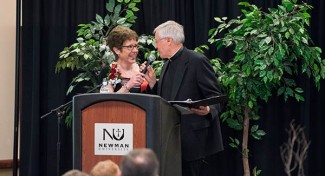 Father Tom Welk hands off the mic to Melissa Grelinger at the Cardinal Newman Banquet Saturday, Feb. 27.