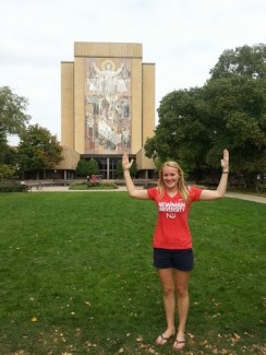 Sporting a Newman University shirt, Liz Peuchen stands in front of iconic "Touchdown Jesus" on the Notre Dame campus.