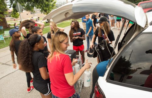 Volunteers help unload a car during new student move-in day.