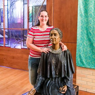 Sister Jenny Sellaro, ASC, stands with a statue of Saint Maria De Mattias.