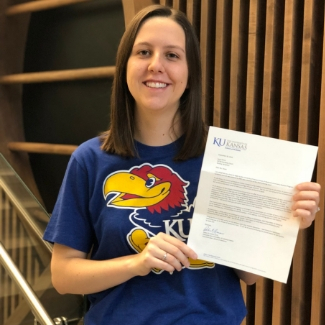 Laura Shine proudly holding her acceptance letter from KU medical school.