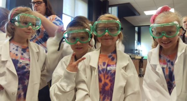 Second graders in lab coats and googles pose for picture