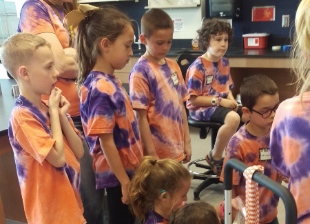 Second graders gather around to listen to instructions for activity.