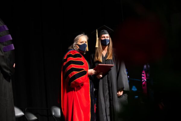 Newman University President Kathleen Jagger, Ph.D., presents a degree to a 2021 graduate.