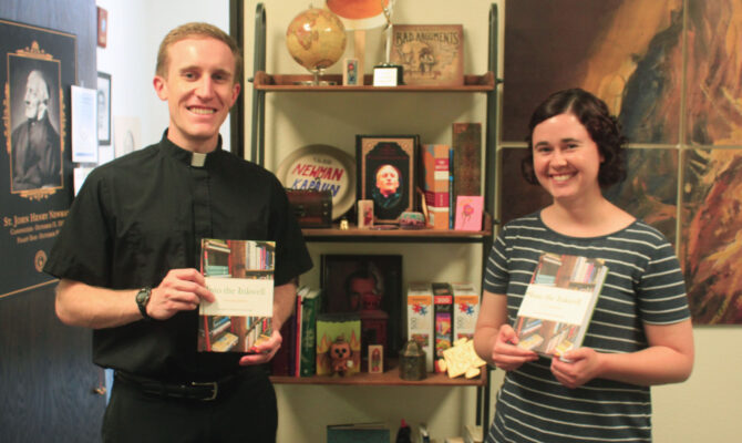 Father Adam Grelinger and Emily Simon hold bound copies of "Into the Inkwell."
