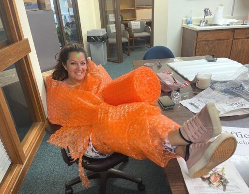 Field Director Adrienne Canno is all wrapped up in bright orange bubble wrap.