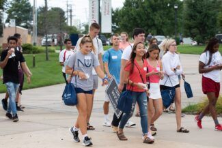 students eagerly walk onto campus in Newman University gear.