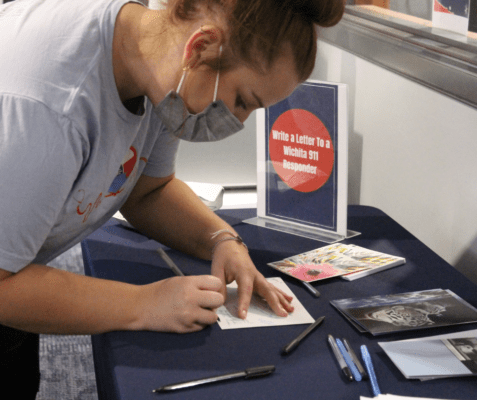 A student signs a thank you letter to 911 responders.