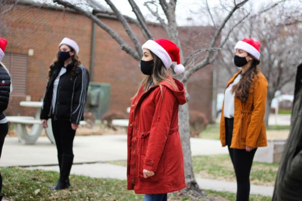 Talia Powers (in red coat) sings Christmas carols with fellow Troubadours.
