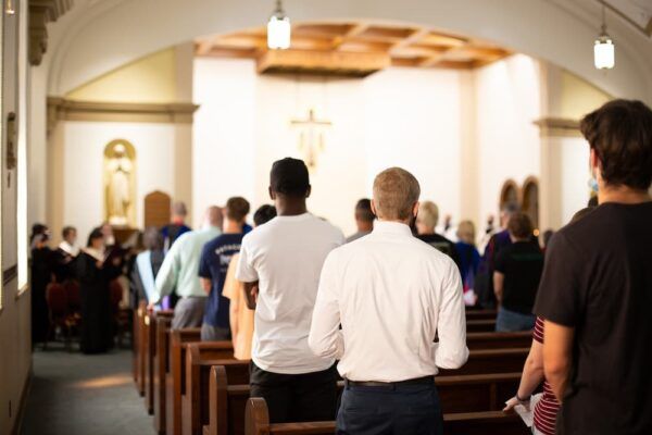 Students stand in the pews during the Mass of the Holy Spirit.