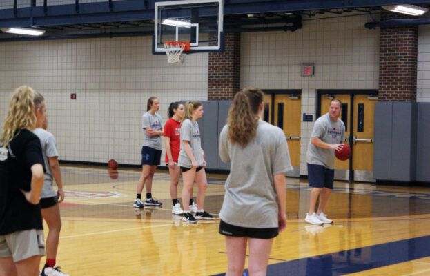 Coach Drew (far right) gives a lesson on passing to attendees of the summer basketball camp.