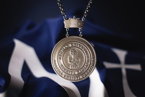 At the heart of the Presidential Medallion is the original seal of the university, complete with the lamp of learning with a "blazing" cross and accompanying motto "Caritas Christi Urget Nos," meaning "The Charity of Christ Urges Us." 