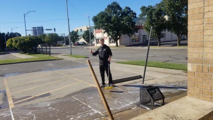 A member of the men's soccer team helps clean the outside of the Lord's Diner.