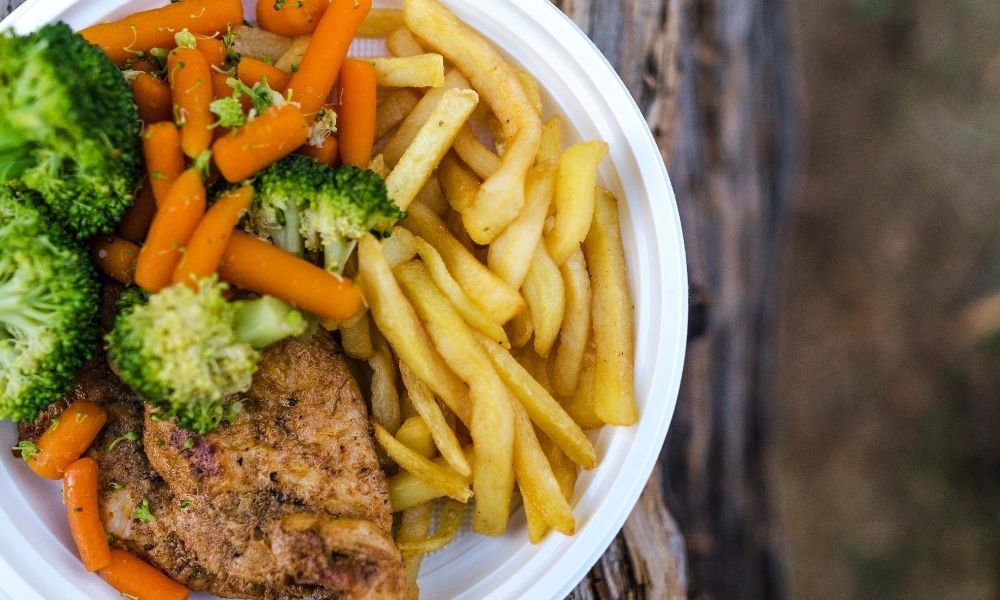 Plate of food with fries, carrots, broccoli, and meat.