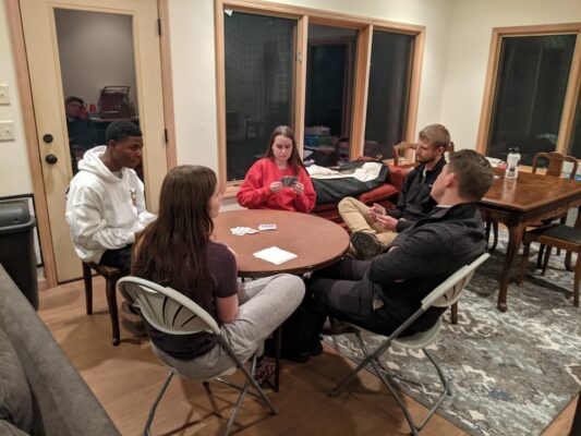 Students play a game of cards at the cabin at Lake Kahola.