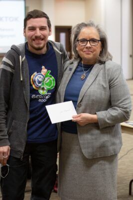 (From right to left) Newman President Kathleen Jagger presents student John Suffield with his award for winning the visual arts contest.