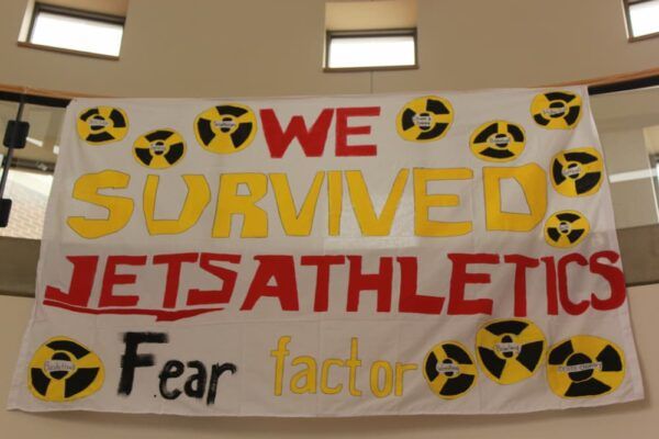 Banner reads "We Survived Jets Athletics Fear Factor" in red and yellow paint
