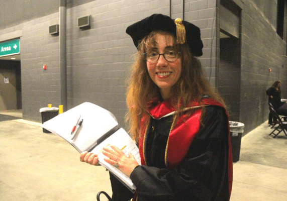 Susan Crane-Laracuente referred to the list of graduates' names and practiced pronunciation before the ceremony.