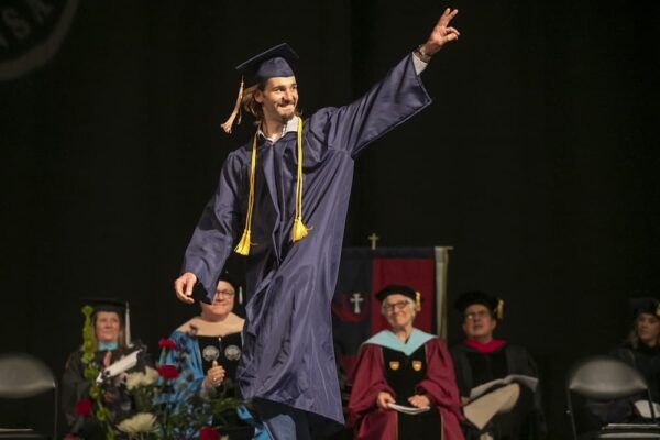 Newman graduate excitedly walks across the stage during Commencement May 6.