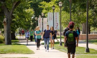 Newman University students walk across the campus sidewalks.