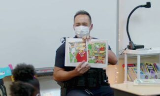 Newman alumnus and Officer Kristopher Gupilan reads to students