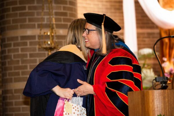 Brittany Stahnke accepts the 2022 Teaching Excellence Award from Newman University President Kathleen Jagger.
