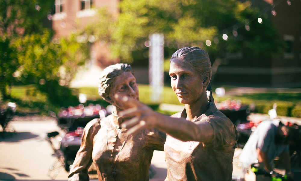 A sculpture of St. Maria DeMattias guiding a student stands at the center of Founder's Plaza at Newman University.