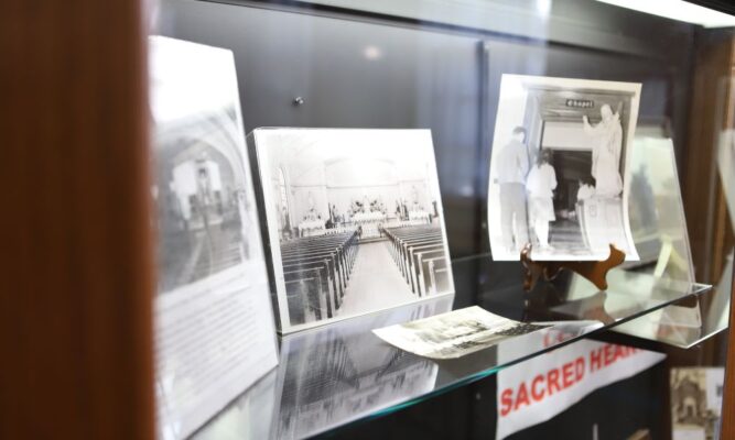 Artifacts and photos from Sacred Heart Hall's history line the shelves in the Heritage Room display case.