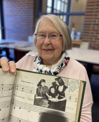 Regina holds a yearbook opened to a page with her photo.