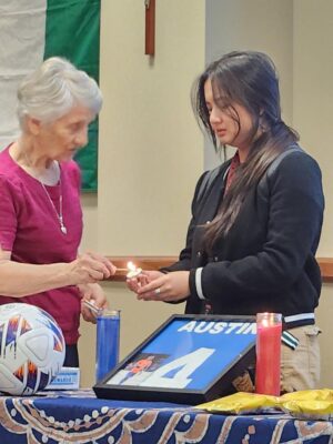 (From left to right) Sister Therese Wetta, ASC, and student Britney Ma light a candle in honor of Madubuike.