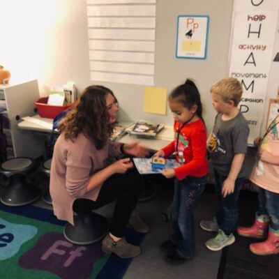 Aliyah Reeves hands a new book to a kindergartener. (Courtesy photo)