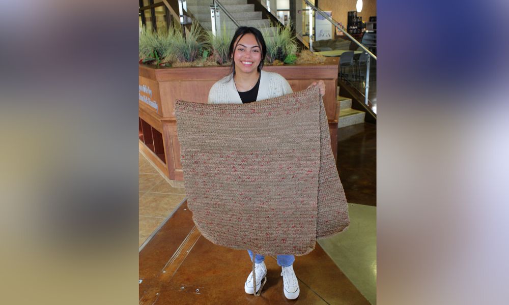 Emelie Nickel holds up a completed mat made from plastic bags at Newman University.