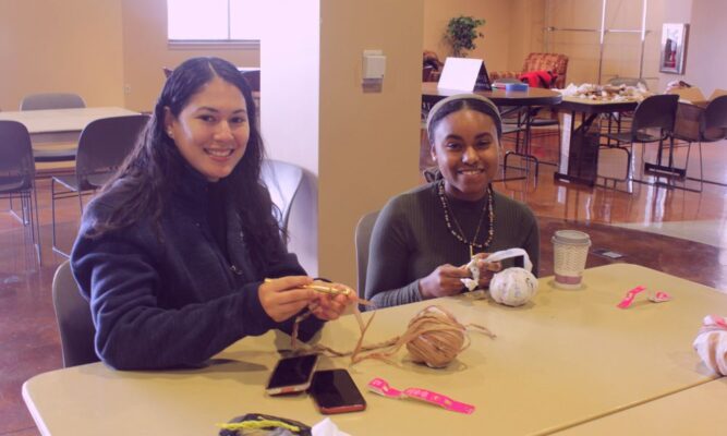 Admissions Counselor Katherine Reynoso and student Meya Warren crochet plarn during Laudato Si' service event.