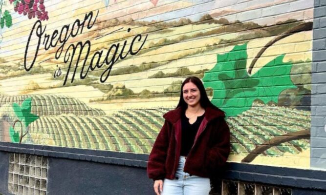Lauren Esfeld stands in front of a mural that reads "Oregon is Magic" (Courtesy photo)