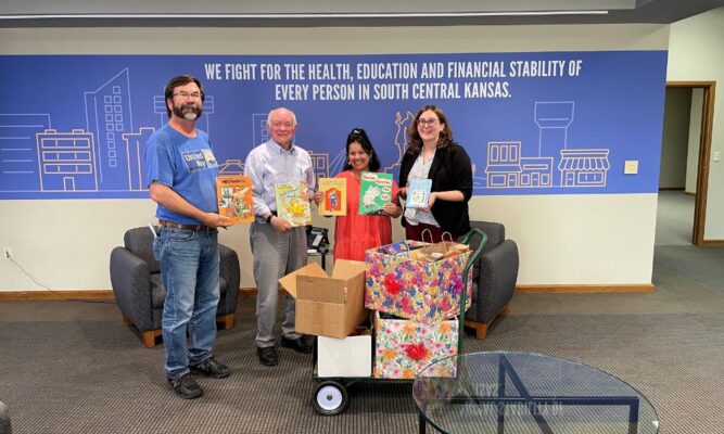Heck (second from left) shows off books donated to United Way on behalf of Pi Gamma Mu's book drive. 