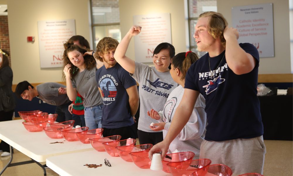 Student Catherine Madison (center) waves her hand in triumph during the minute-to-win-it games.