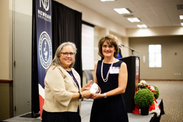 Christine Ostroski (right) receives the 2023 St. Maria De Mattias Award from Newman President Kathleen Jagger.