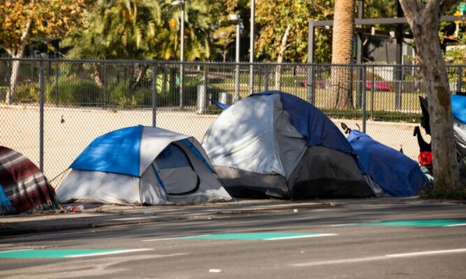 Unhoused individuals sleep in tents near downtown Wichita.