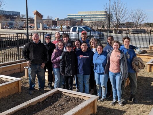 The group poses with their completed fence in the center's garden. 