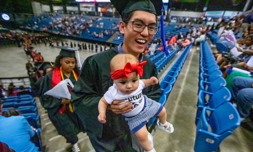 Matthew Nguyen carries his daughter following Newman commencement May 12.