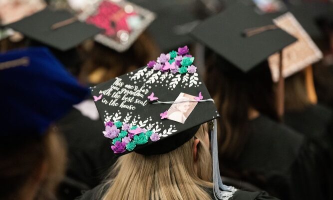 A graduate's decorative cap reads, "This one's for you, grandma, with the best seat in the house."