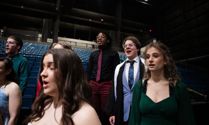 Schwartz sings with members of the Newman chorale at commencement May 12.