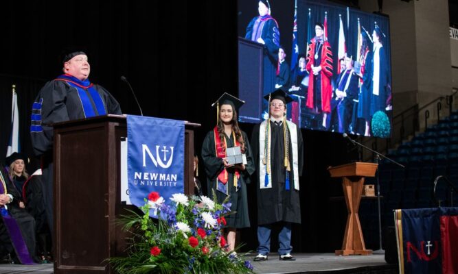 Vice President of Academic Affairs Alden Stout invites Ablah Award winners Talia Powers and Austin Schwartz to the stage at commencement.