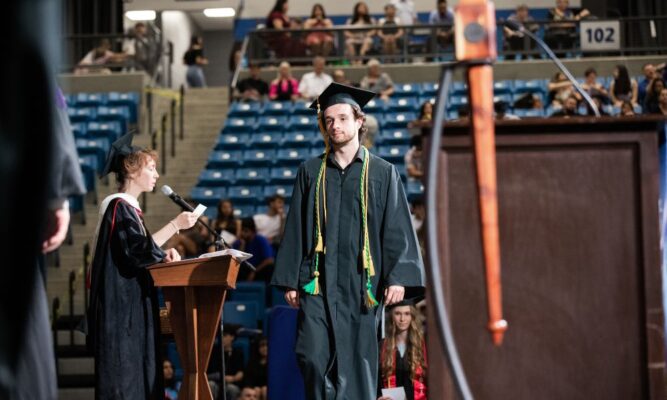 Newman University biology graduate Luke Sanders '23 walks the stage at Newman commencement May 12.