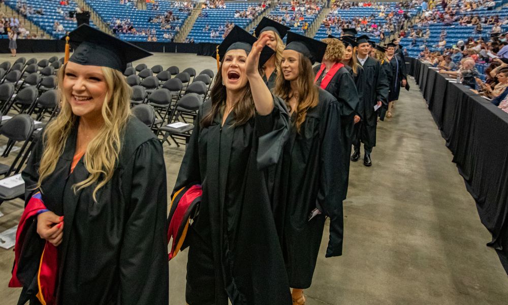 Newman University graduates wave in excitement as they exit the arena.