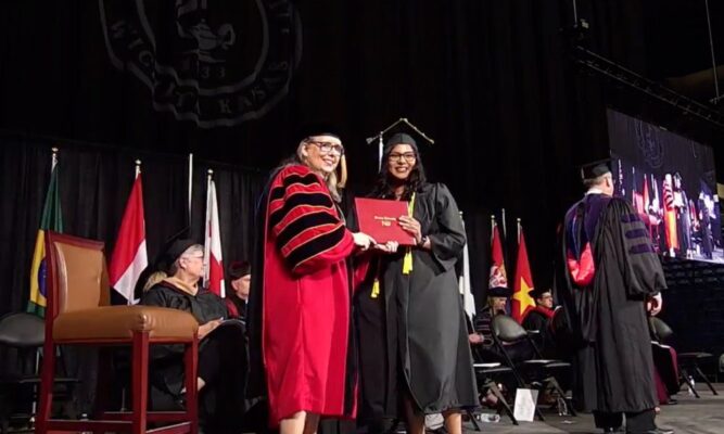 Imelda Blackburn accepts her diploma from Newman University President Kathleen Jagger.