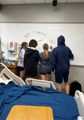 Students brainstorm answers to the question "What is nursing?" on a whiteboard in Bishop Gerber.