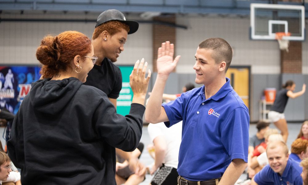 Students high-five during international student orientation at Newman University.