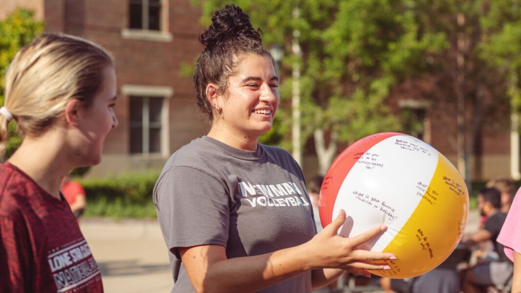 A smiling female student holds up a beach ball with questions on it during a game at the Back to School Bash.